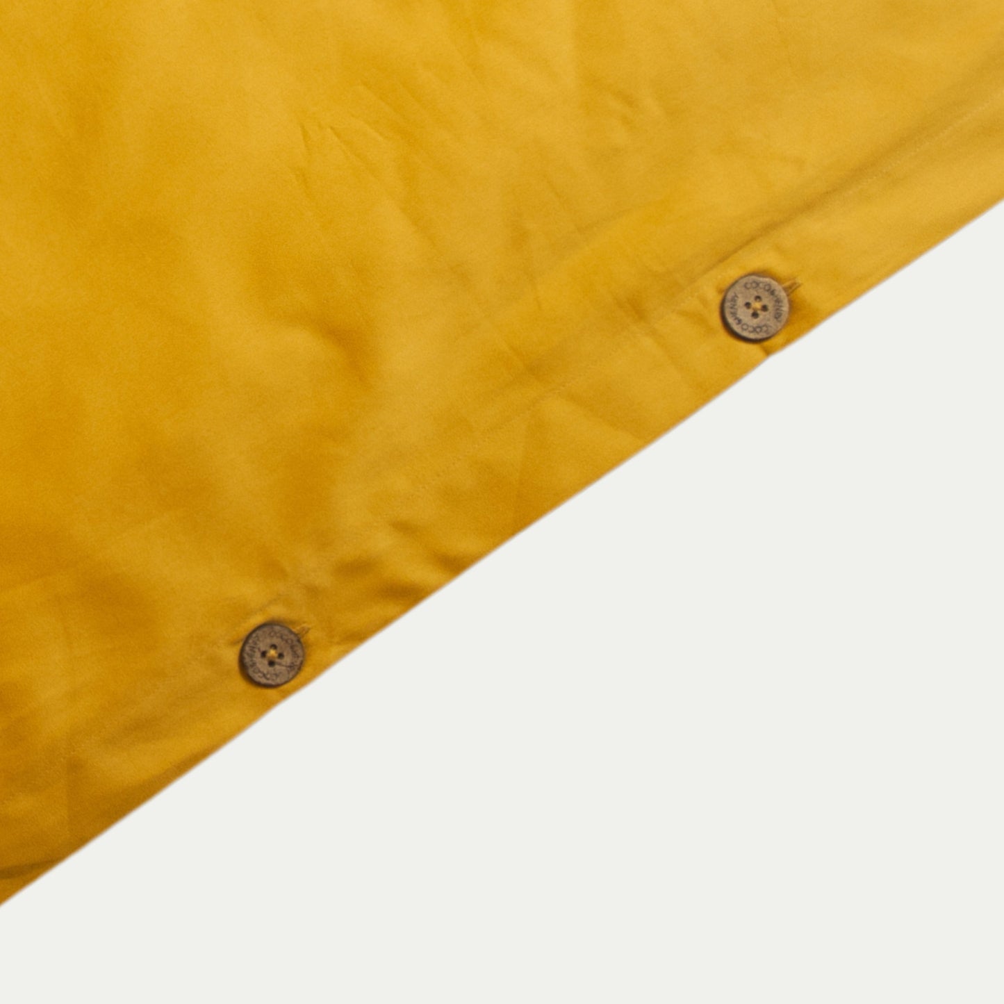 Close up of quilt cover edge with coconut buttons in honey gold