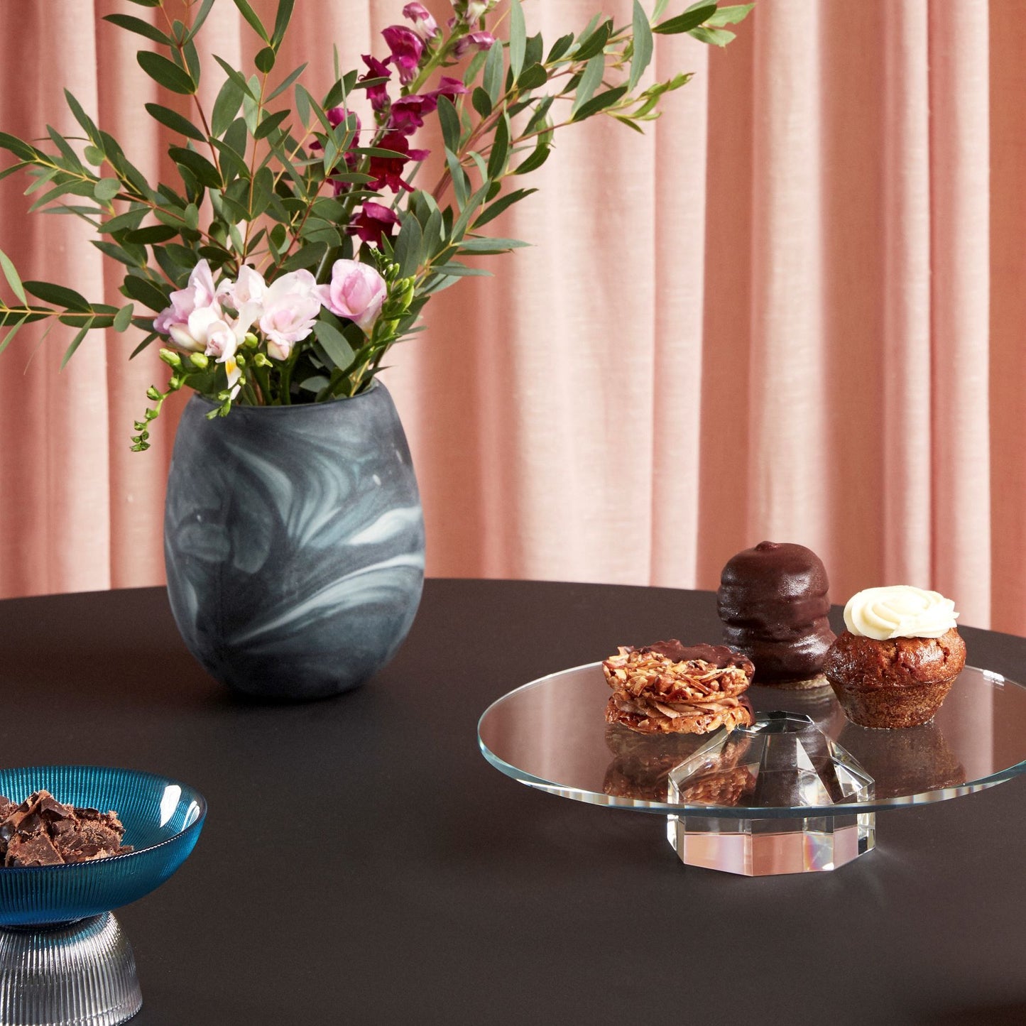 Hubsch Interior Scandi style marbled vase in white and dark green glass with flower arrangement on dining table with cakes