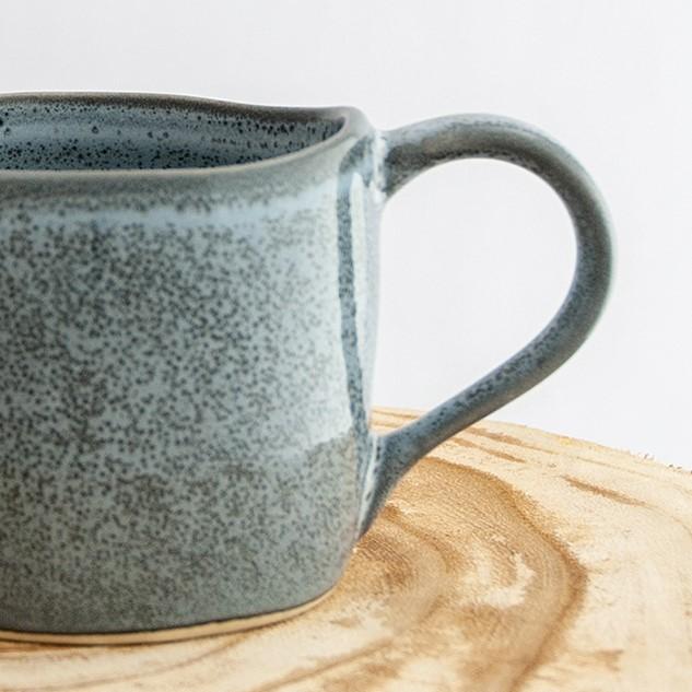 Close up of a Robert Gordon storm grey organic mug coffee cup sitting on a natural wooden round side table